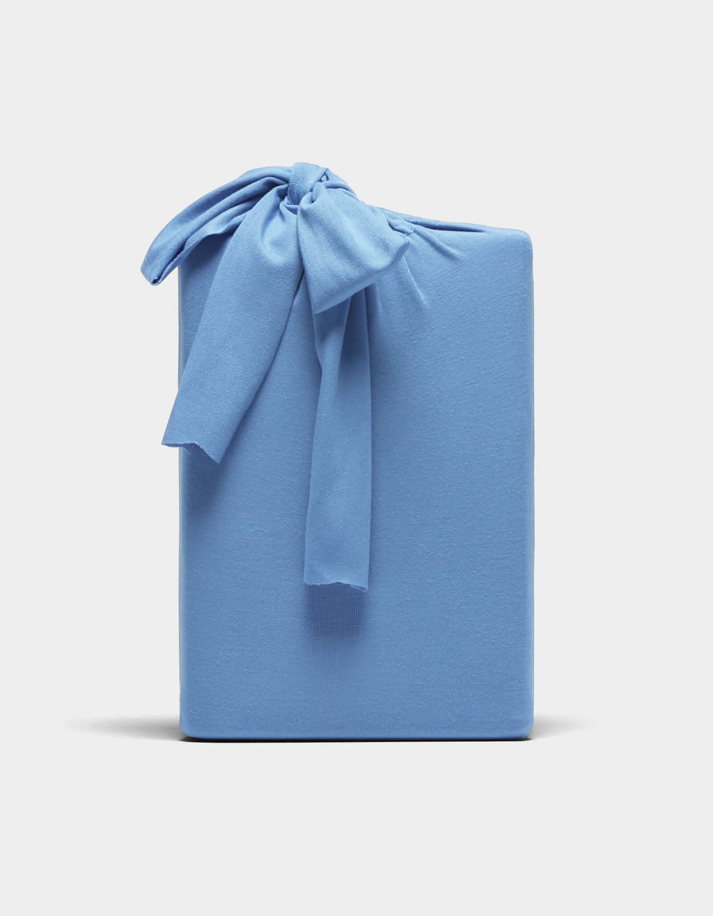 A Bamboo Jersey Sheet Set by Cozy Earth, neatly folded and wrapped in light blue fabric with a matching bow, displayed against a plain white background.|Color:Sailor