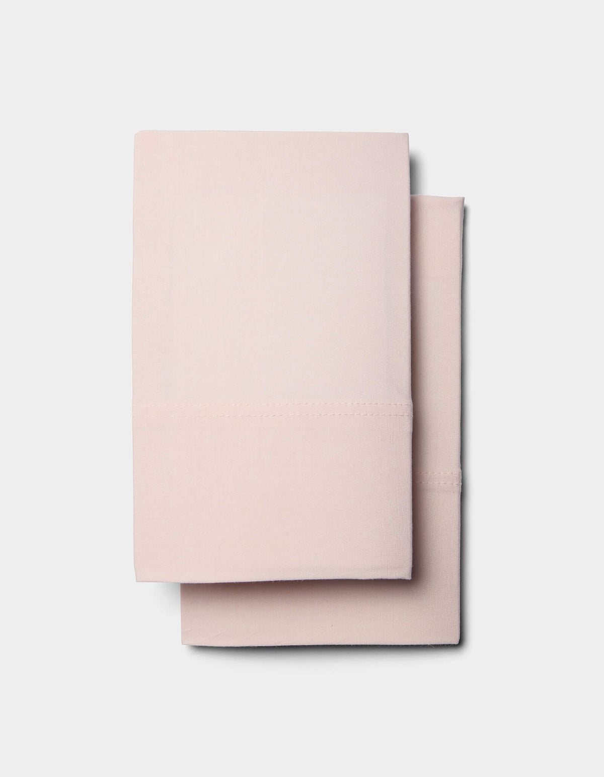 Two neatly folded, light pink Cozy Earth Bamboo Jersey Pillowcases stacked together against a plain white background.|Color:Petal