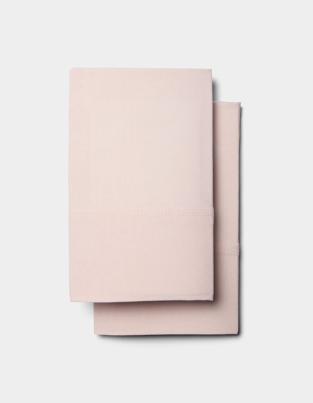 Two neatly folded Cozy Earth Bamboo Jersey Sheet Sets in light pink are stacked on top of each other against a plain white background.|Color:Petal