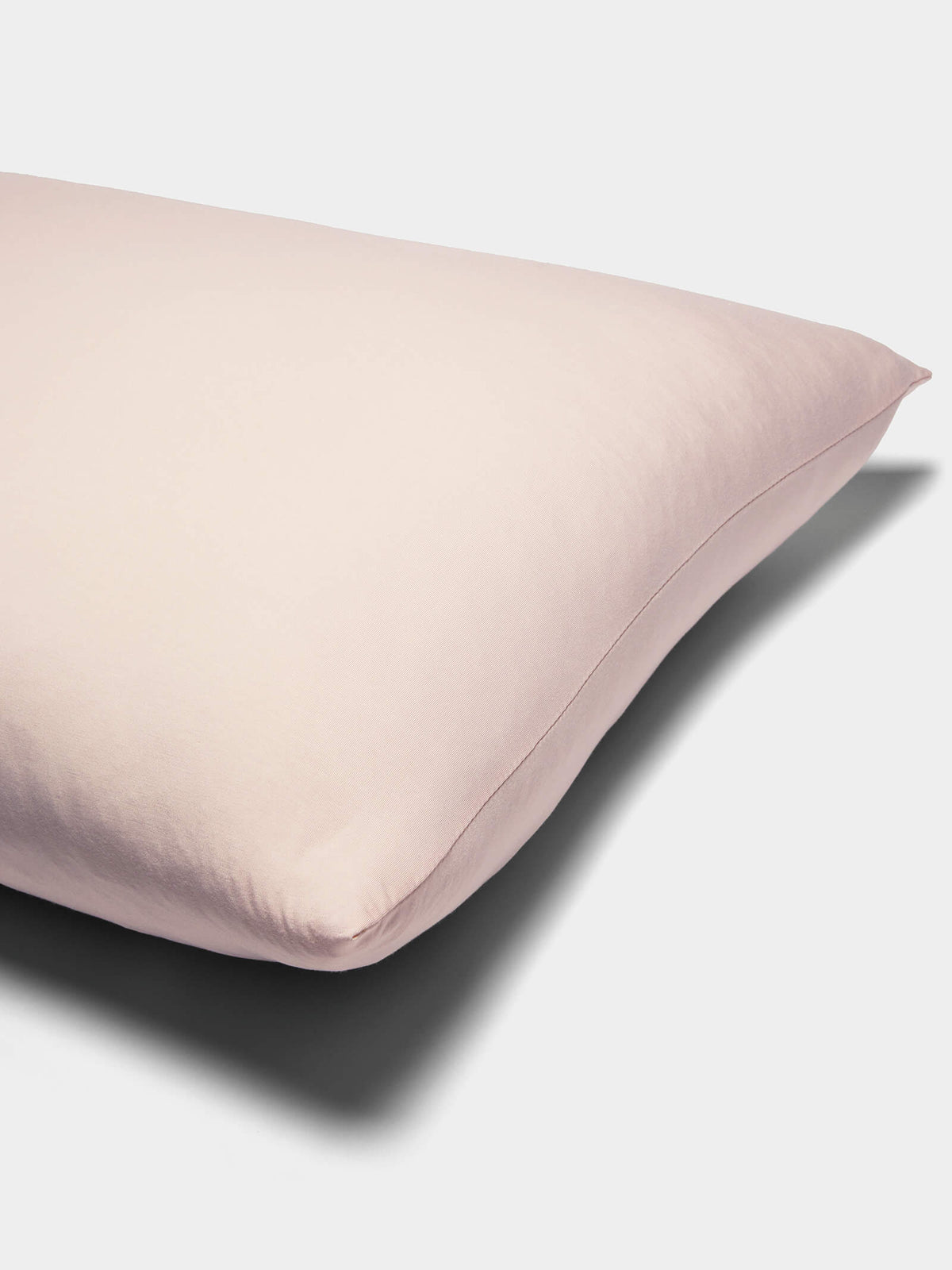 A close-up of Cozy Earth Bamboo Jersey Pillowcases in pale pink with a smooth, soft fabric cover, shown against a plain white background.|Color:Petal