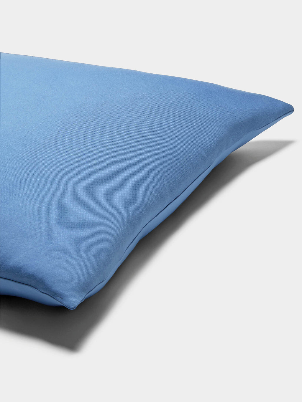 A close-up of a Cozy Earth Bamboo Jersey Pillowcase displays its smooth blue fabric against a plain white background.|Color:Sailor