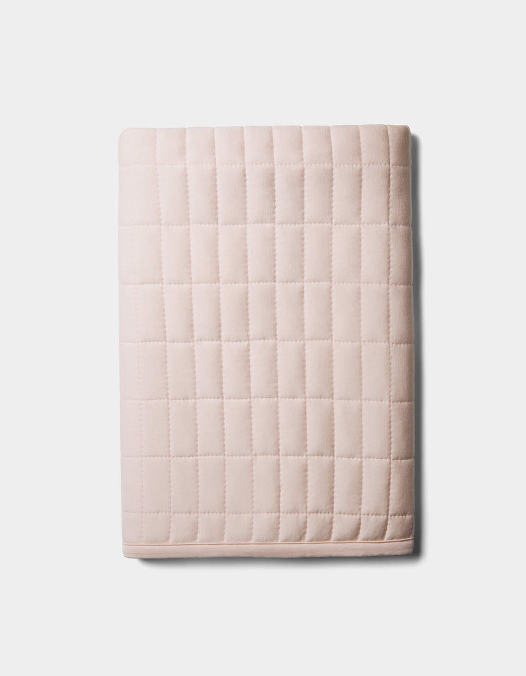 The Bamboo Jersey Quilted Shams by Cozy Earth, in light pink with a square grid pattern, are neatly folded and displayed on a plain white background.|Color:Petal