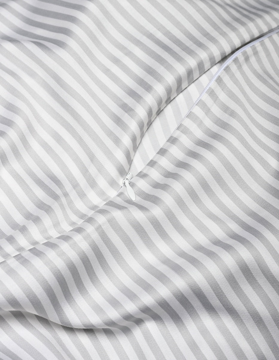 A close-up of the Cozy Earth Bamboo Duvet Cover in white and gray stripes, featuring a partially unzipped zipper that reveals its smooth, shiny texture and soft folds.|Color:Classic Stripe in Dew