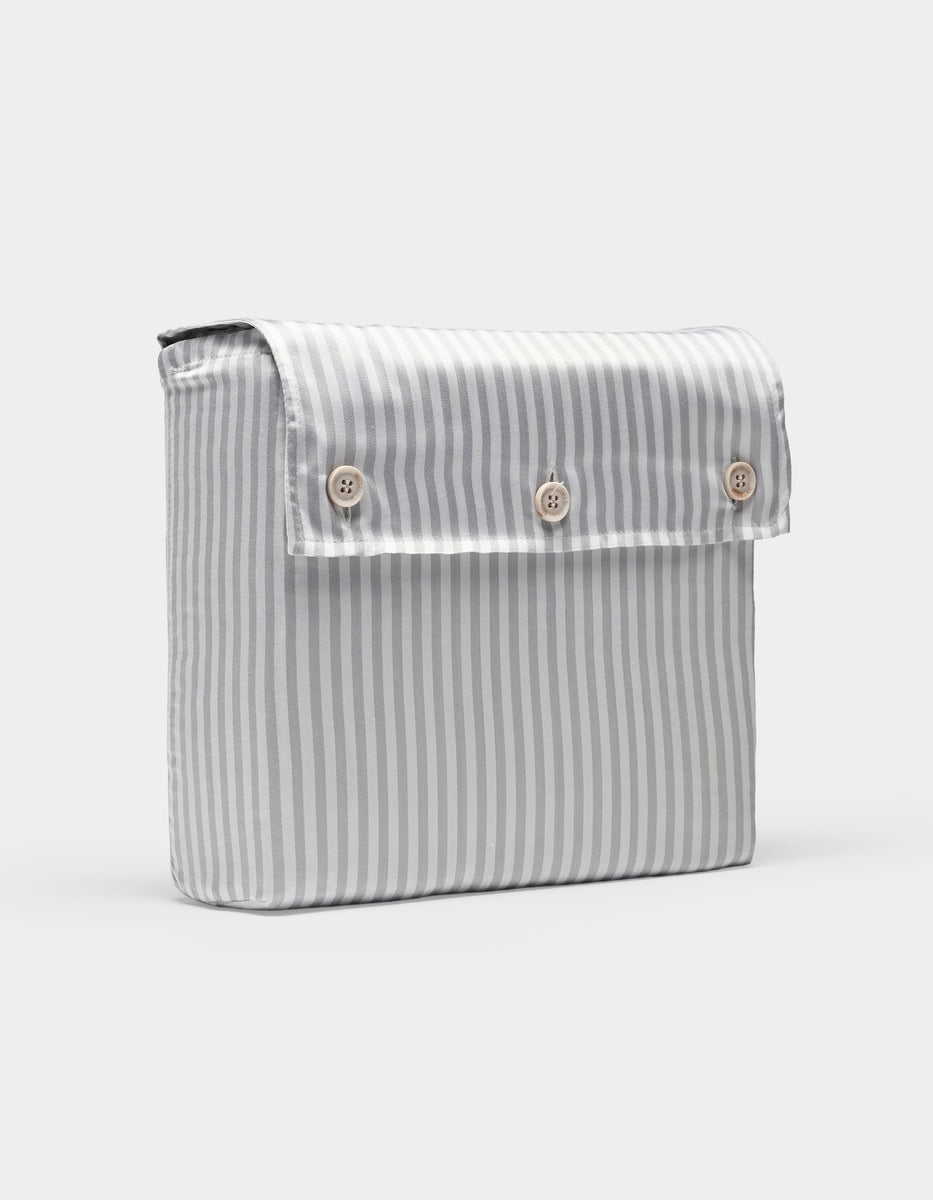 A Bamboo Sheet Set by Cozy Earth featuring vertical gray and white stripes and a rectangular fabric pouch with a flap secured by three light-colored buttons on the front.|Color:Classic Stripe in Dew