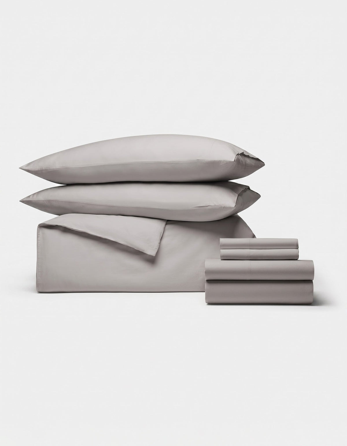 The Cozy Earth Soft-Wash Cotton Bedding Core Bundle features two pillows, a folded duvet, and two sets of folded sheets in light gray, all neatly stacked and displayed on a plain white background.|Color:Dew