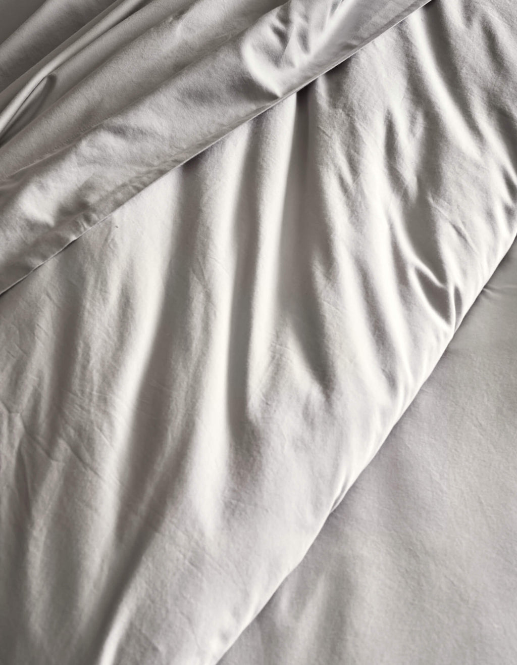 A close-up of the Cozy Earth Soft-Wash Cotton Duvet Set in light gray, featuring gentle folds and creases for a textured, cozy look.|Color:Dew