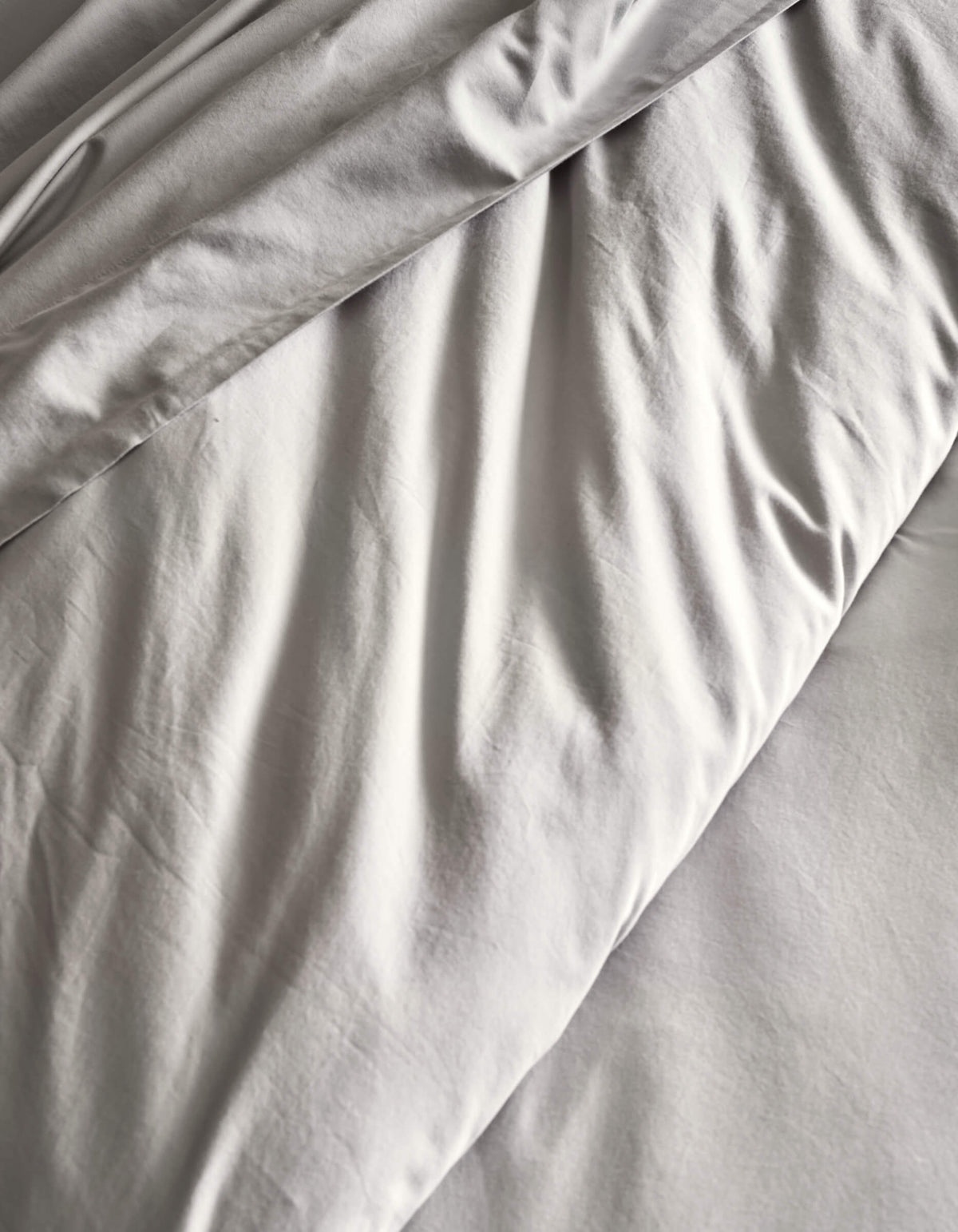 A close-up of the Cozy Earth Soft-Wash Cotton Duvet Set in light gray, featuring gentle folds and creases for a textured, cozy look.|Color:Dew