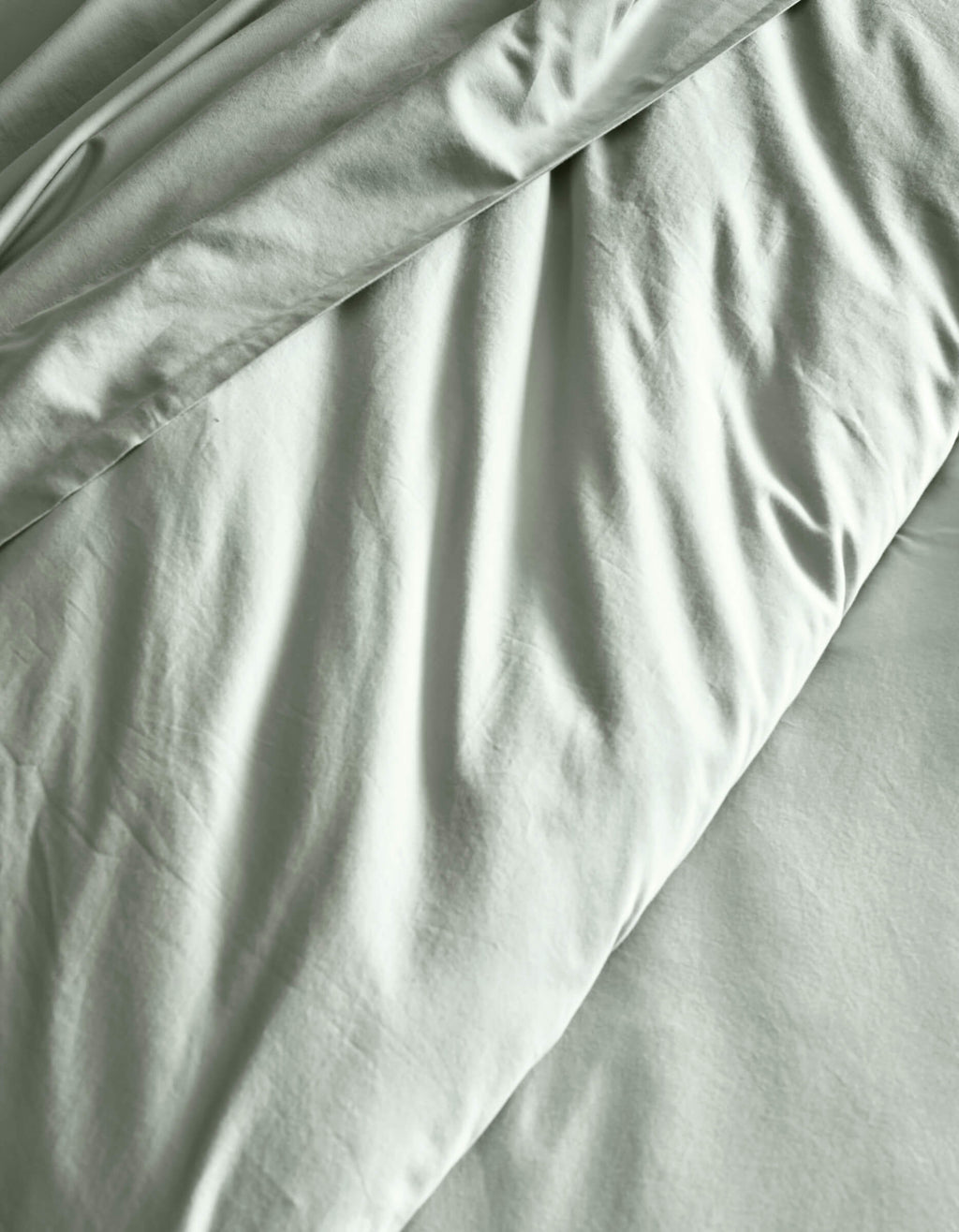The Soft-Wash Cotton Duvet Cover by Cozy Earth features a light gray finish with subtle wrinkles and gentle folds, creating soft shadows across the fabric.|Color:Laurel