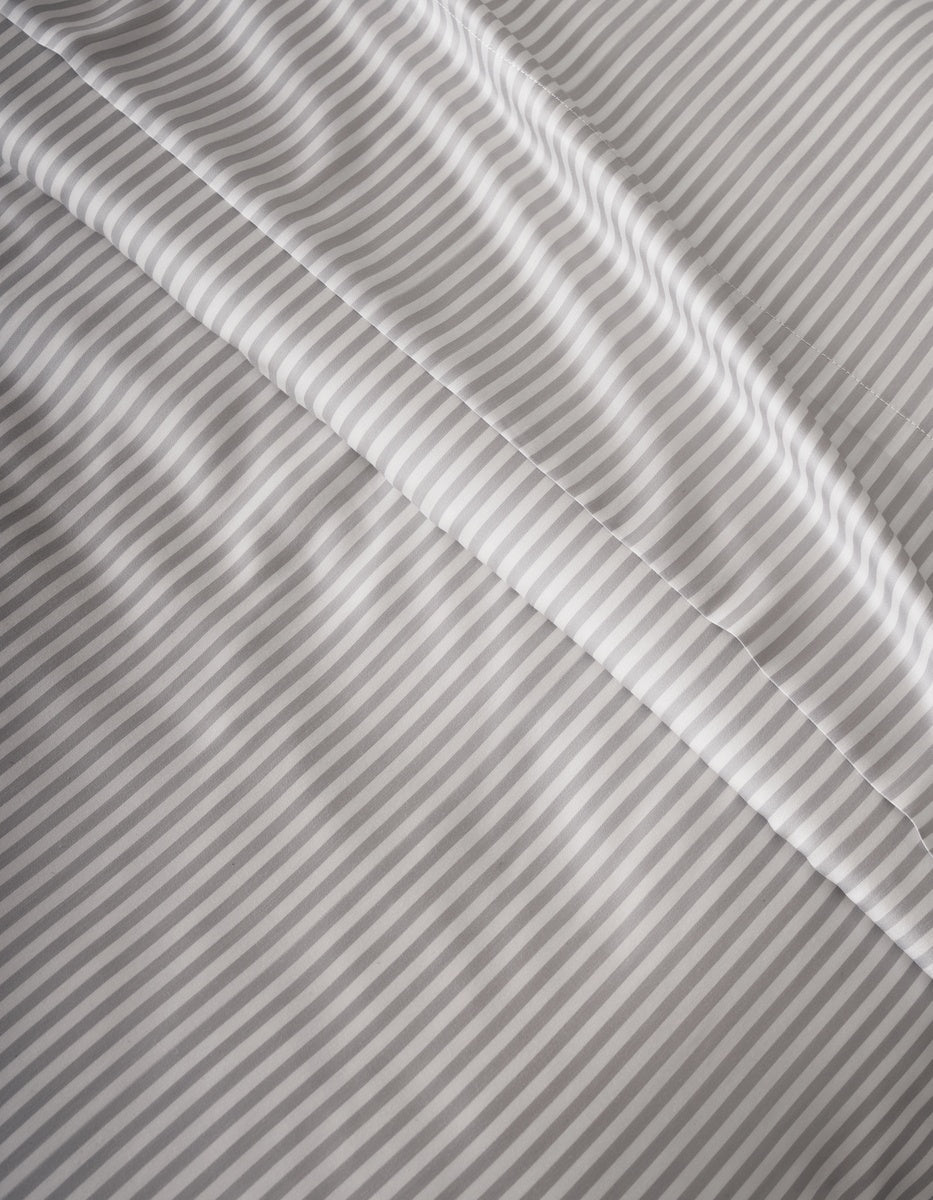 Close-up of Cozy Earth’s Bamboo Duvet Cover in light gray and white stripes, featuring a smooth texture with gentle folds and diagonal lines across the surface.|Color:Classic Stripe in Dew
