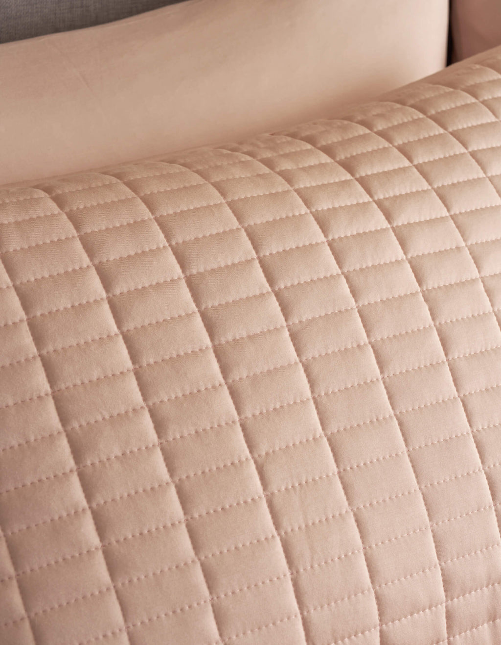 Close-up of Cozy Earth Bamboo Jersey Quilted Shams, showing a beige quilted fabric with a grid pattern of stitched lines. The texture and stitching of this soft, elegant sham are clearly visible.|Color:Petal