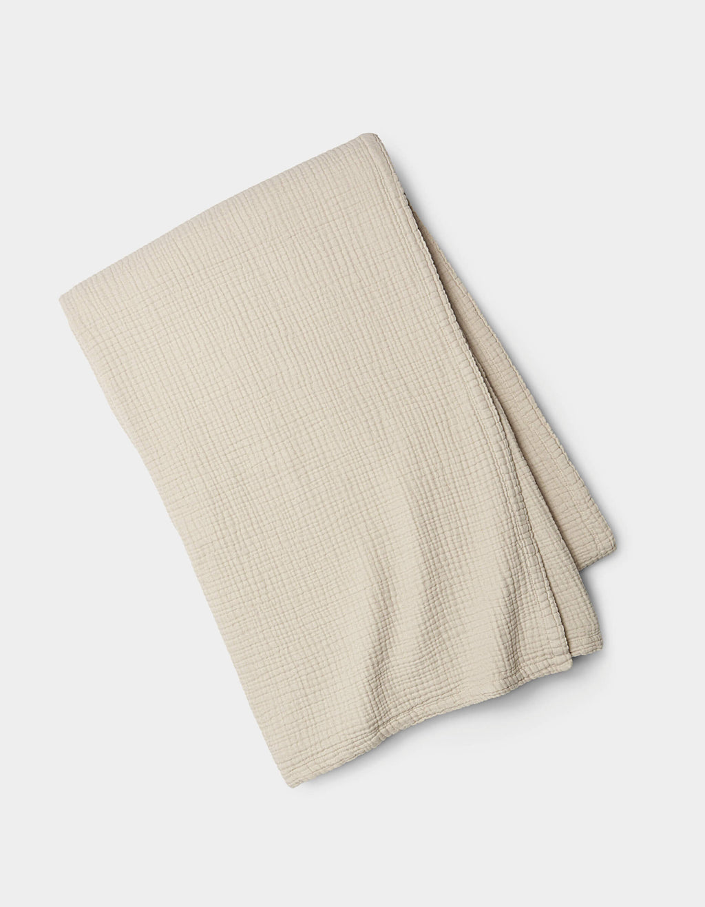 The Cozy Earth Cotton Gauze Blanket, light beige with a subtle grid texture, is neatly folded and displayed on a white background.|Color:Coconut
