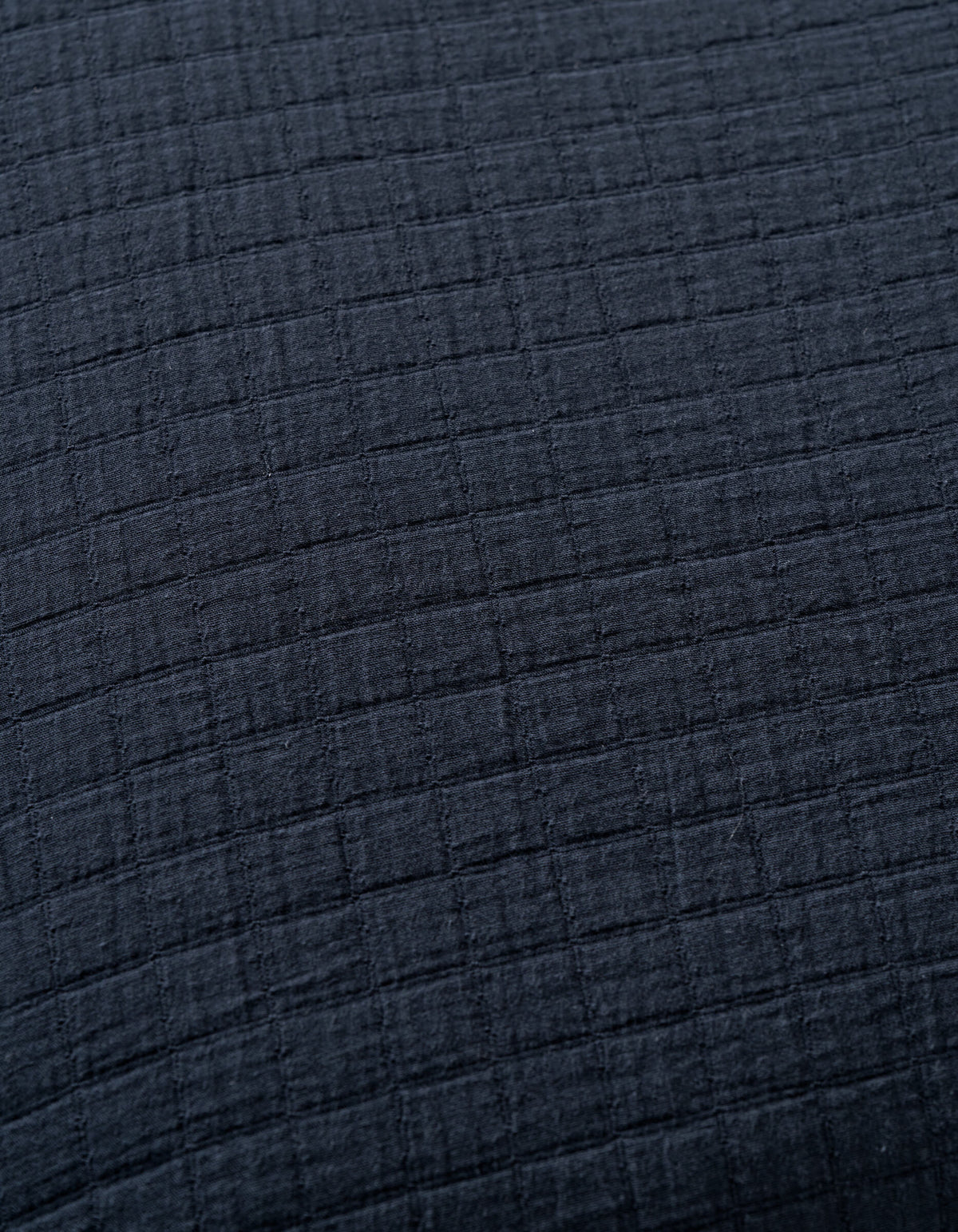 Close-up of Cozy Earth's Waterfront Grid Matelasse Blanket in dark gray or black, featuring a soft textured fabric with a subtle grid pattern formed by raised horizontal and vertical lines.|Color:Eclipse