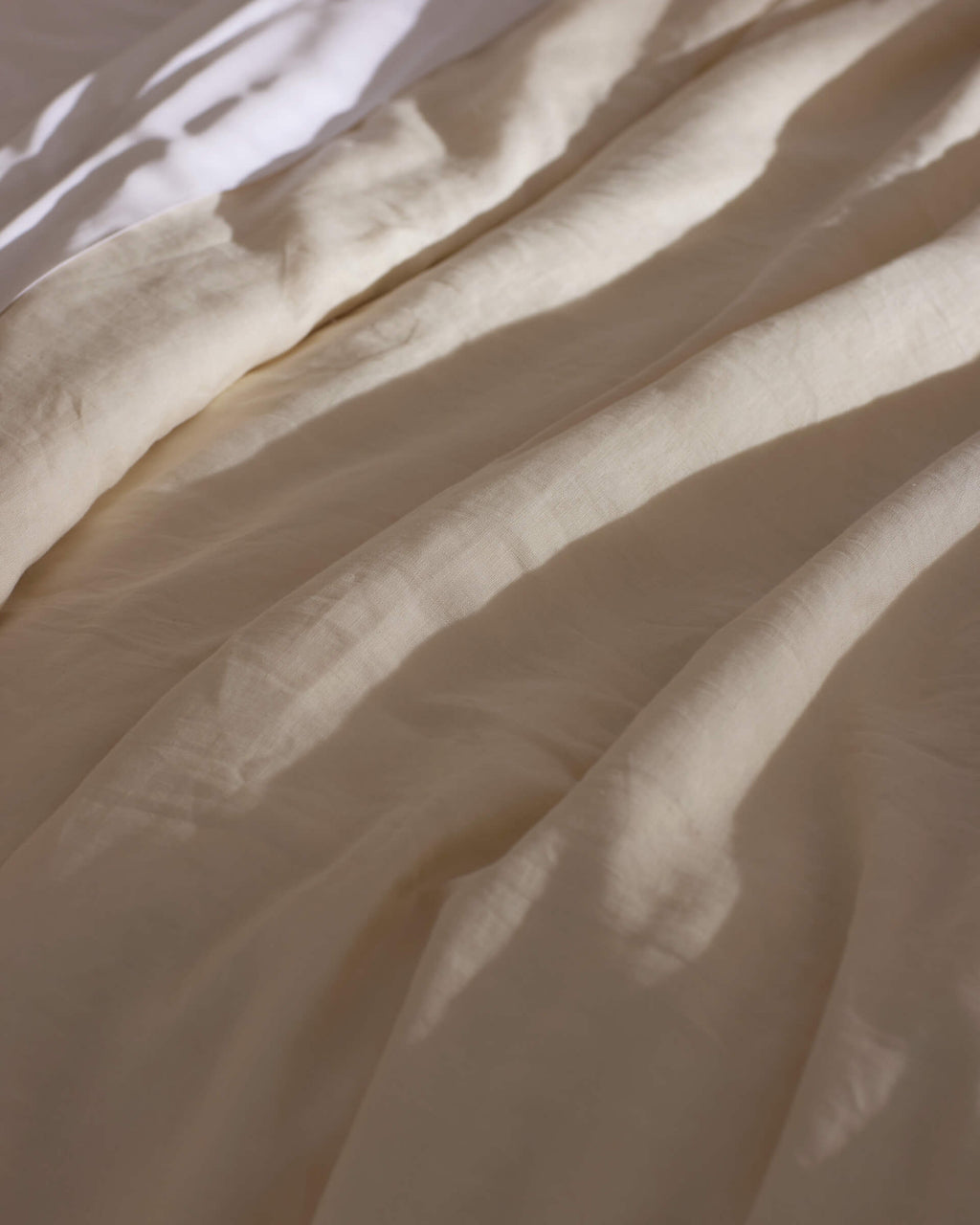 Soft sunlight casts gentle shadows across Cozy Earth's Linen Duvet Cover, creating a calm and cozy atmosphere.|Color:Flax