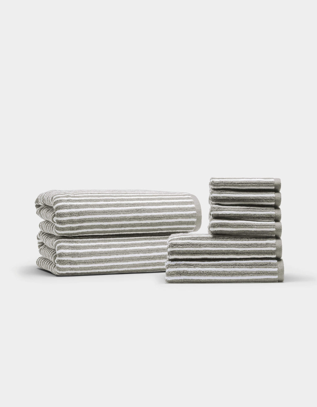 Two neatly arranged stacks of the Cozy Earth Ribbed Terry Bath Towel Set are displayed on a plain white background—one larger stack featuring bath towels, and a smaller stack showcasing hand towels and washcloths.|Color:Dew Stripe