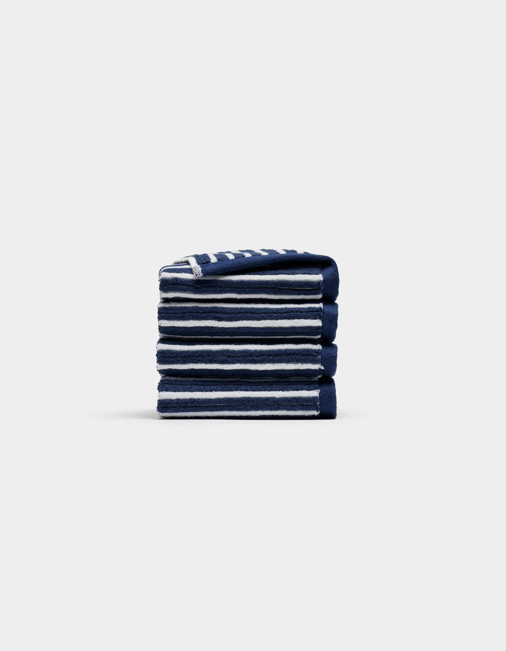 A neatly folded stack of four Cozy Earth Ribbed Terry Washcloths in navy blue and white stripes is centered on a plain, light gray background.|Color:Obsidian Stripe