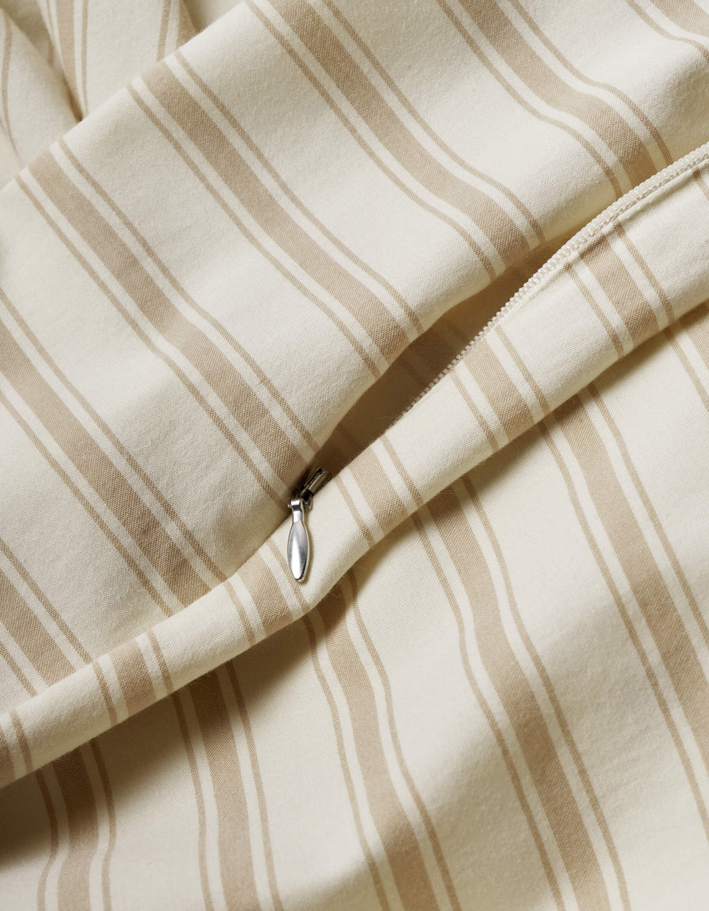 A close-up of the Cozy Earth Soft-Wash Cotton Duvet Cover shows beige and cream vertical stripes, a smooth texture, and a partially open visible zipper.|Color:Coconut and Sandalwood Stripe