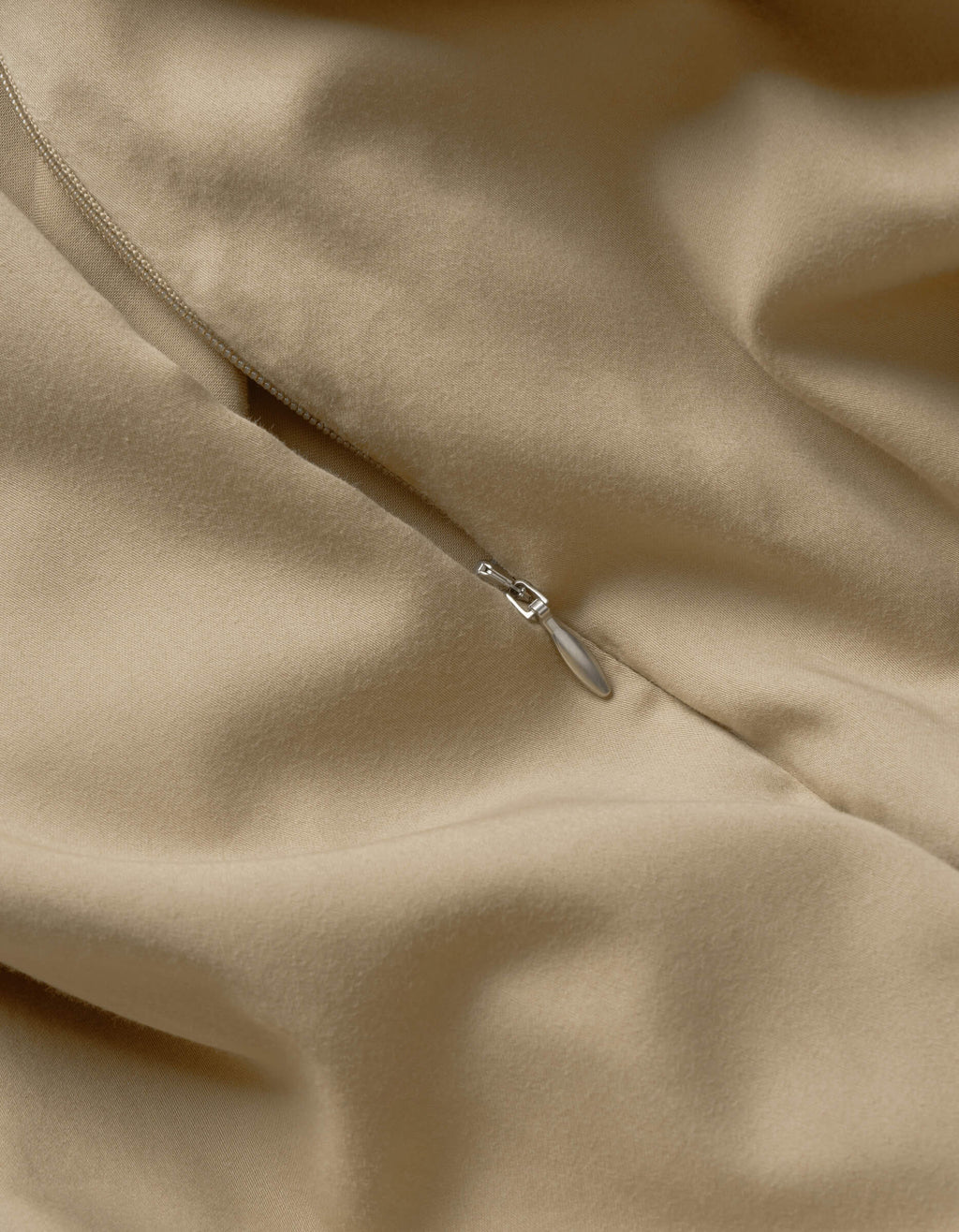 Close-up of Cozy Earth’s Soft-Wash Cotton Duvet Cover in beige, highlighting its smooth texture, soft folds, and a partially closed silver zipper.|Color:Sandalwood
