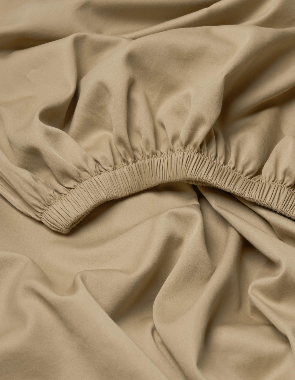 The Cozy Earth Soft-Wash Cotton Fitted Sheet features beige fabric with elasticated ruching, forming gathered folds for a soft, textured look. The smooth, slightly shiny material is arranged in loose, overlapping layers.|Color:Sandalwood