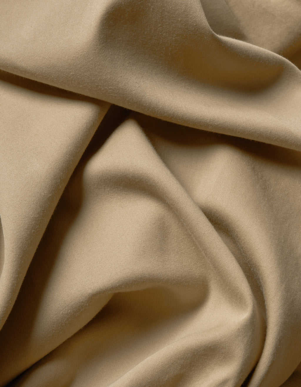 A close-up of Cozy Earth's Soft-Wash Cotton Flat Sheet showcases its soft beige fabric with smooth folds and gentle shadows, highlighting the luxurious texture and movement.|Color:Sandalwood