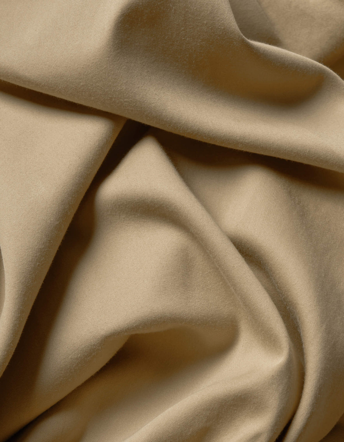 A close-up of Cozy Earth's Soft-Wash Cotton Flat Sheet showcases its soft beige fabric with smooth folds and gentle shadows, highlighting the luxurious texture and movement.|Color:Sandalwood