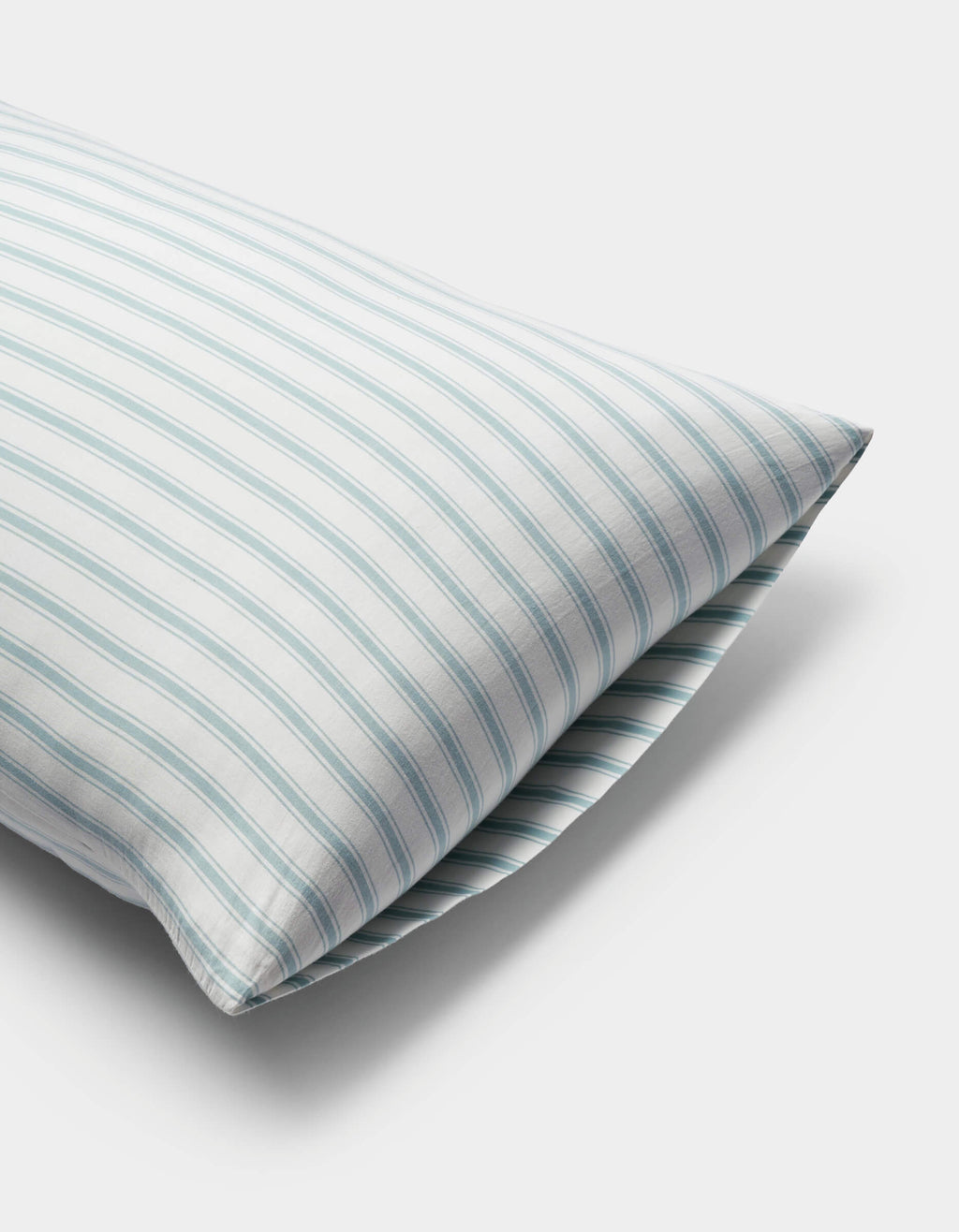 A close-up of a Cozy Earth Soft-Wash Cotton Pillowcase with a white cover and light blue and green vertical stripes, set against a plain white background.|Color:River and Sea Salt Stripe