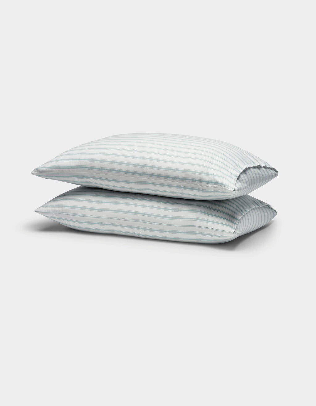 Two Soft-Wash Cotton Pillowcases by Cozy Earth, featuring light blue and white vertical stripes, are stacked against a plain white background.|Color:River and Sea Salt Stripe