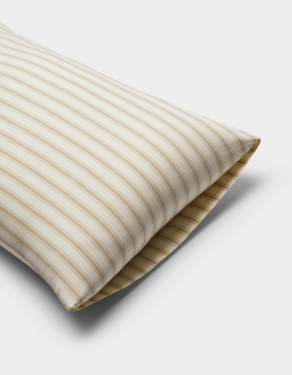 The Cozy Earth Soft-Wash Cotton Pillowcases in beige and white stripes are displayed on a plain white background, partially angled to highlight their soft texture and classic design.|Color:Coconut and Sandalwood Stripe