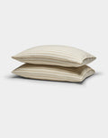 Two Cozy Earth Soft-Wash Cotton Pillowcases in beige with thin horizontal brown stripes are stacked against a plain white background.|Color:Coconut and Sandalwood Stripe