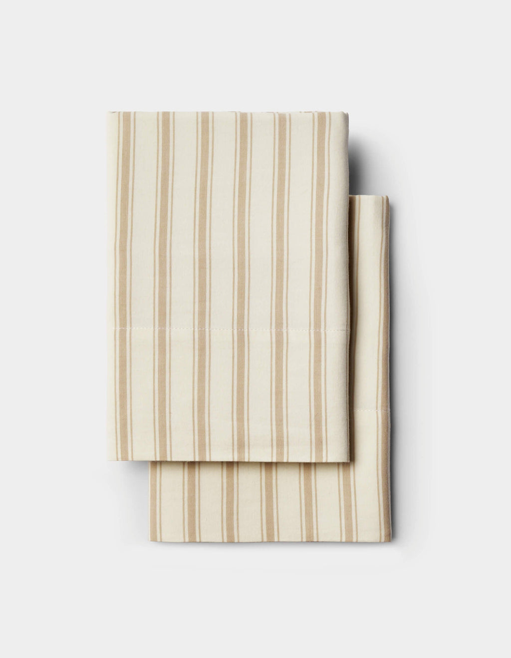 Two folded cream-colored Soft-Wash Cotton Pillowcases by Cozy Earth, featuring thin beige vertical stripes, are stacked neatly on a plain white background.|Color:Coconut and Sandalwood Stripe