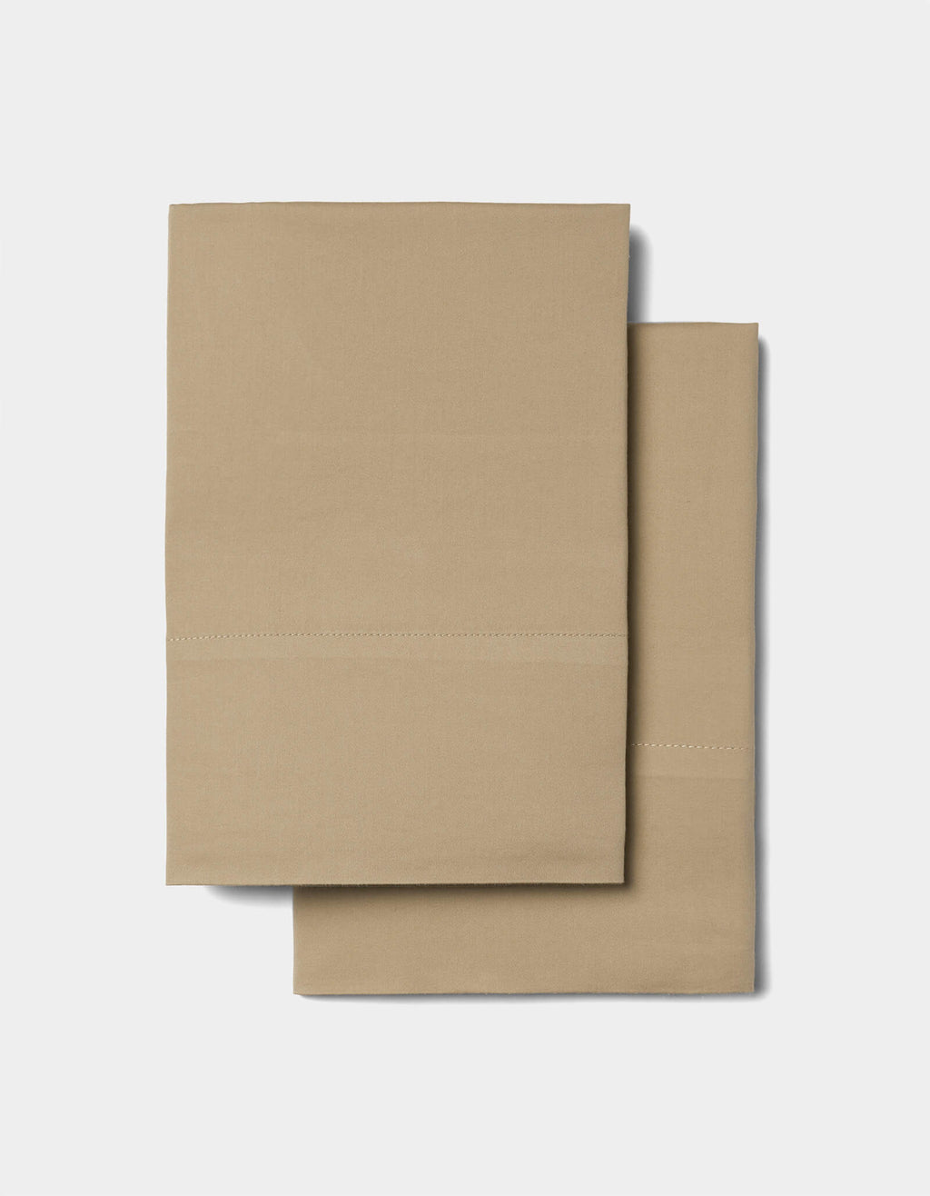 Two folded tan pillowcases from the Cozy Earth Soft-Wash Cotton Sheet Set, featuring a simple stitched line detail, placed on a plain light background.|Color:Sandalwood