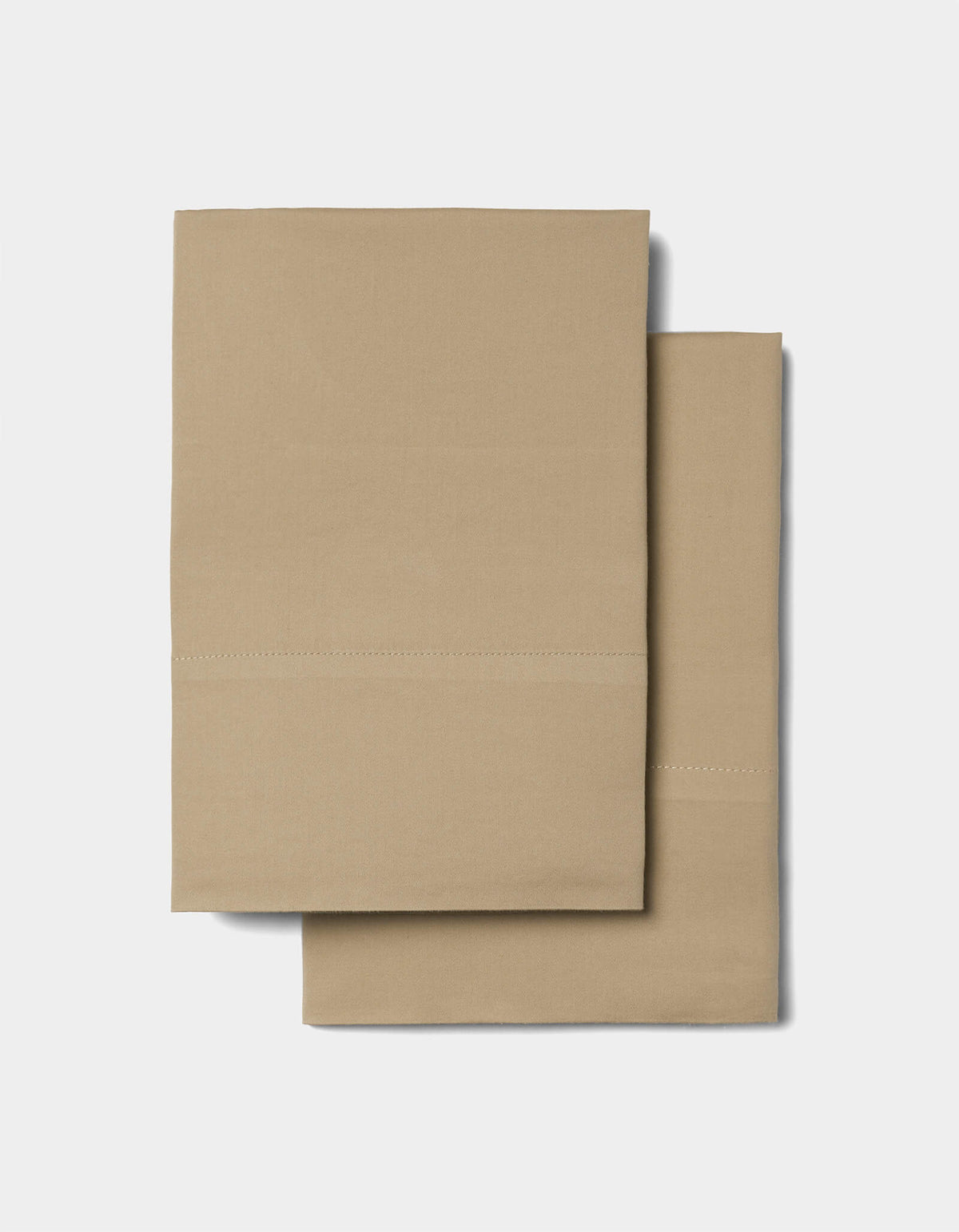 Two folded tan pillowcases from the Cozy Earth Soft-Wash Cotton Sheet Set, featuring a simple stitched line detail, placed on a plain light background.|Color:Sandalwood