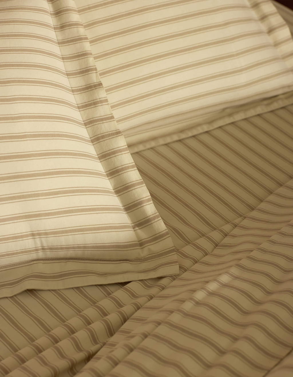 Close-up of a neatly made bed featuring Cozy Earth Soft-Wash Cotton Shams in beige and light brown stripes, highlighting the fabric's texture and precise alignment.|Color:Coconut and Sandalwood Stripe