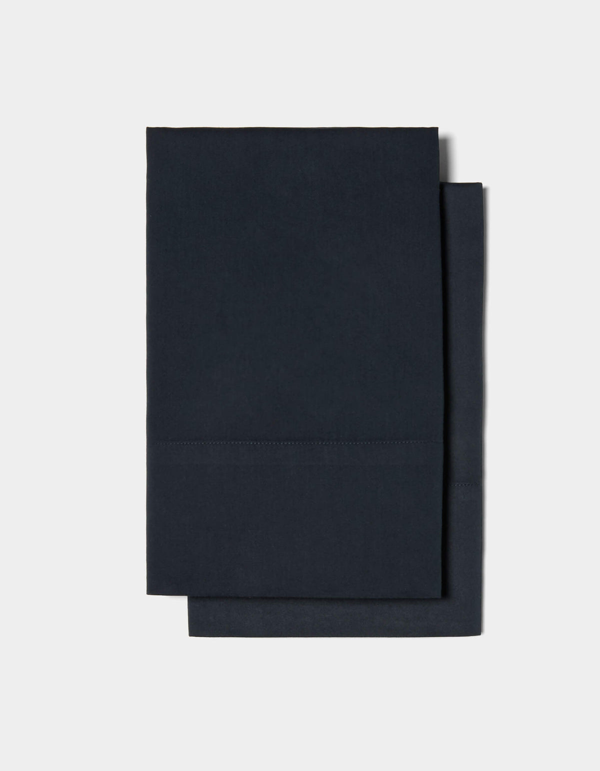 Two neatly folded Soft-Wash Cotton Pillowcases by Cozy Earth are stacked on top of each other against a plain white background.|Color:Eclipse