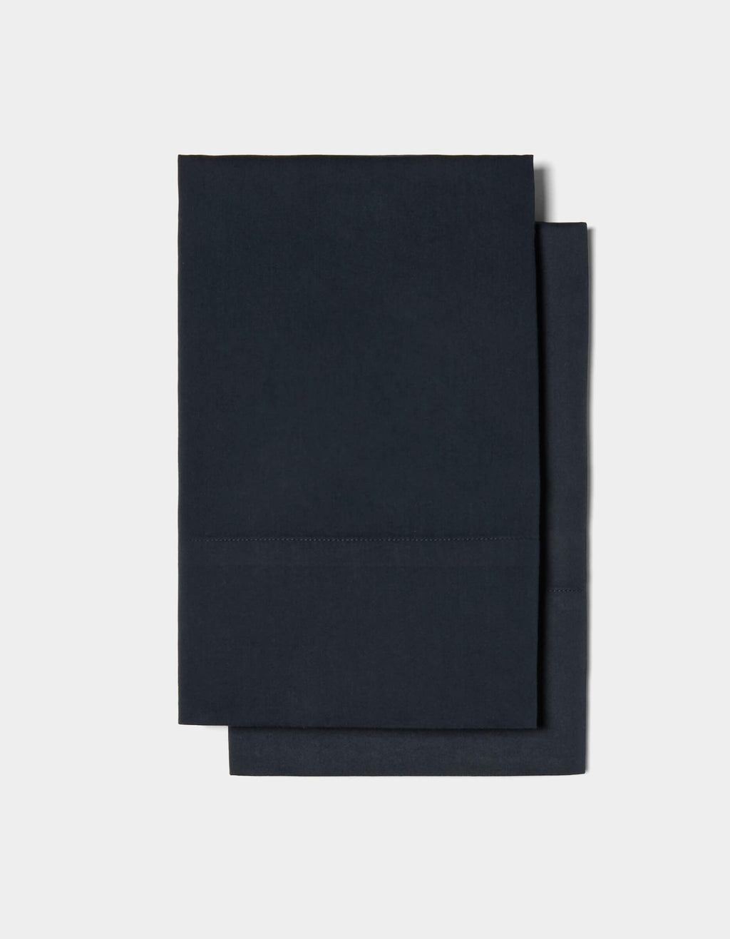 Two neatly folded Soft-Wash Cotton Pillowcases by Cozy Earth are stacked on top of each other against a plain white background.|Color:Eclipse