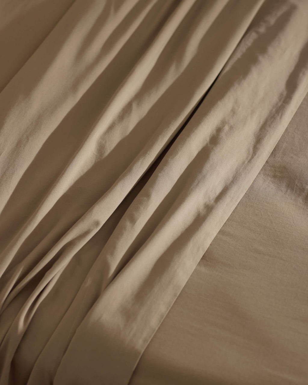 Close-up of Cozy Earth’s Soft-Wash Cotton Sheet Set in beige, highlighting its gentle folds, subtle shadows, and smooth, cozy texture.|Color:Sandalwood