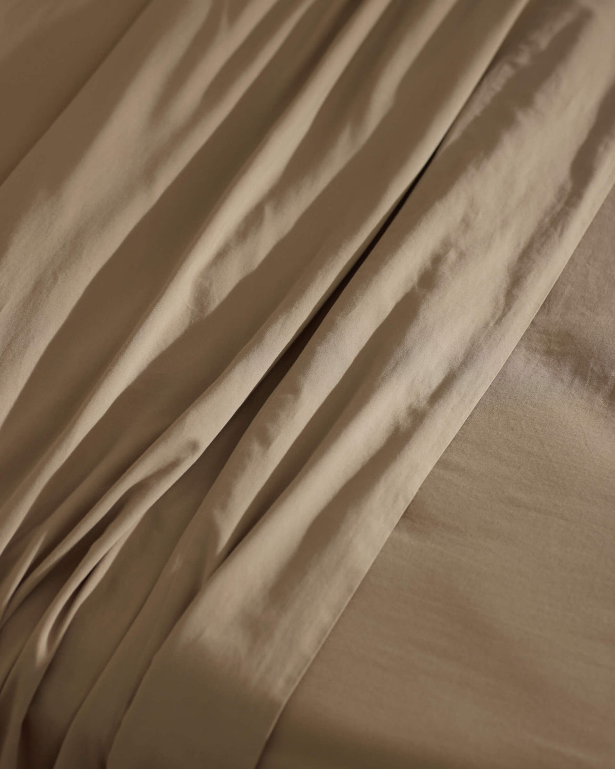 Close-up of Cozy Earth’s Soft-Wash Cotton Sheet Set in beige, highlighting its gentle folds, subtle shadows, and smooth, cozy texture.|Color:Sandalwood
