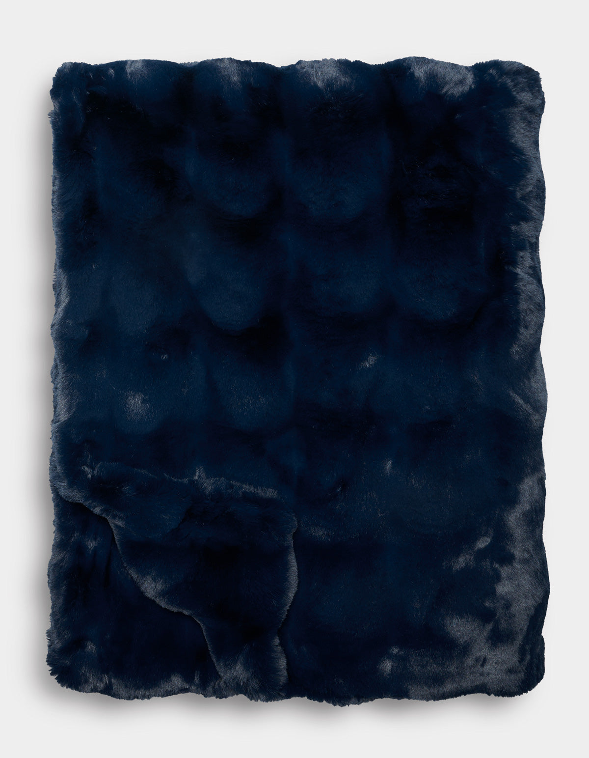 The Double Bubble Cuddle Blanket by Cozy Earth, in dark navy blue faux fur, is folded neatly to display its plush, soft texture and subtle sheen against a plain white background.|Color:Eclipse