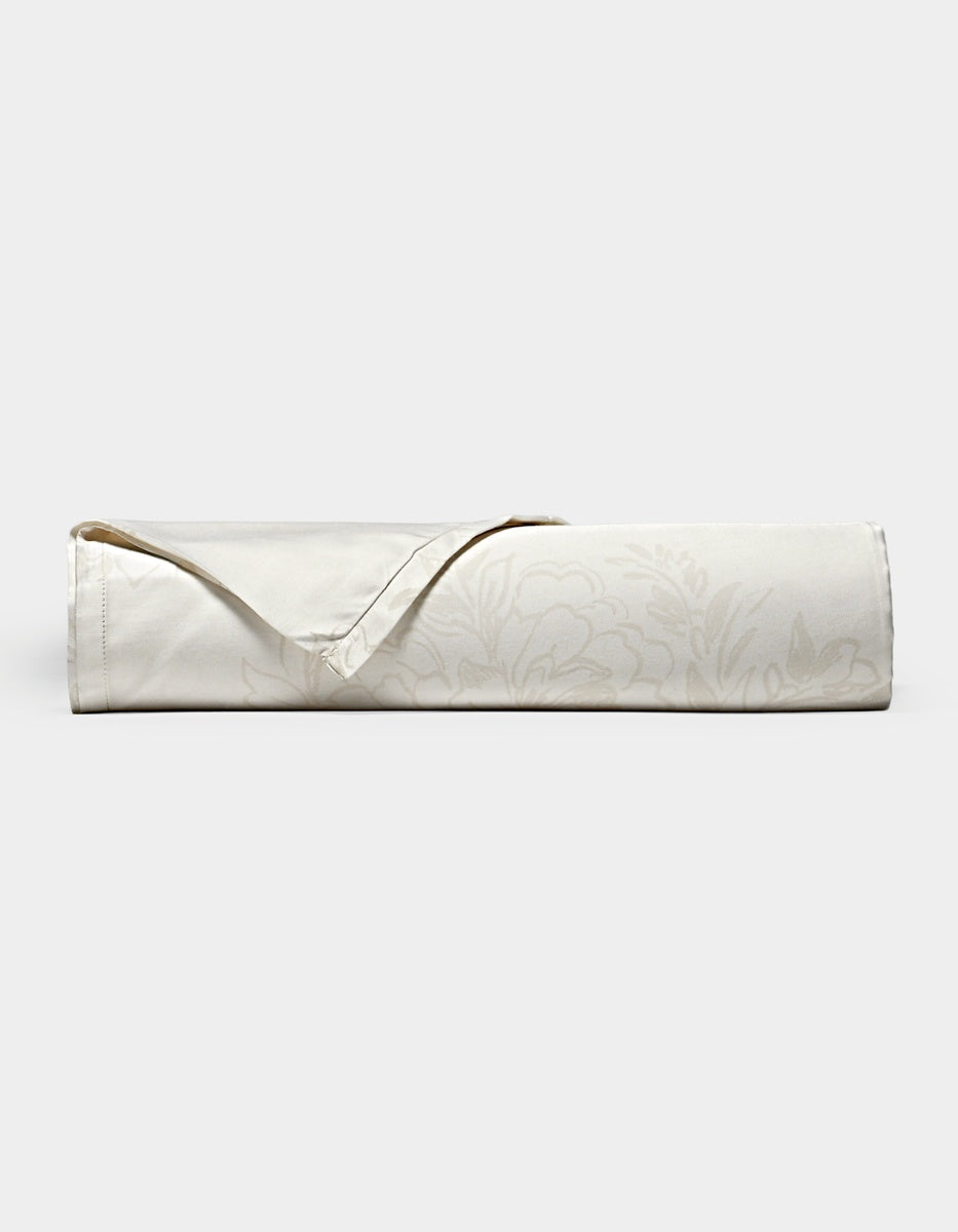 A neatly rolled Cozy Earth Bamboo Flat Sheet in cream, featuring a subtle floral pattern and a folded-back hemmed corner, displayed on a plain white background.|Color:Sonoma Floral in Vintage White
