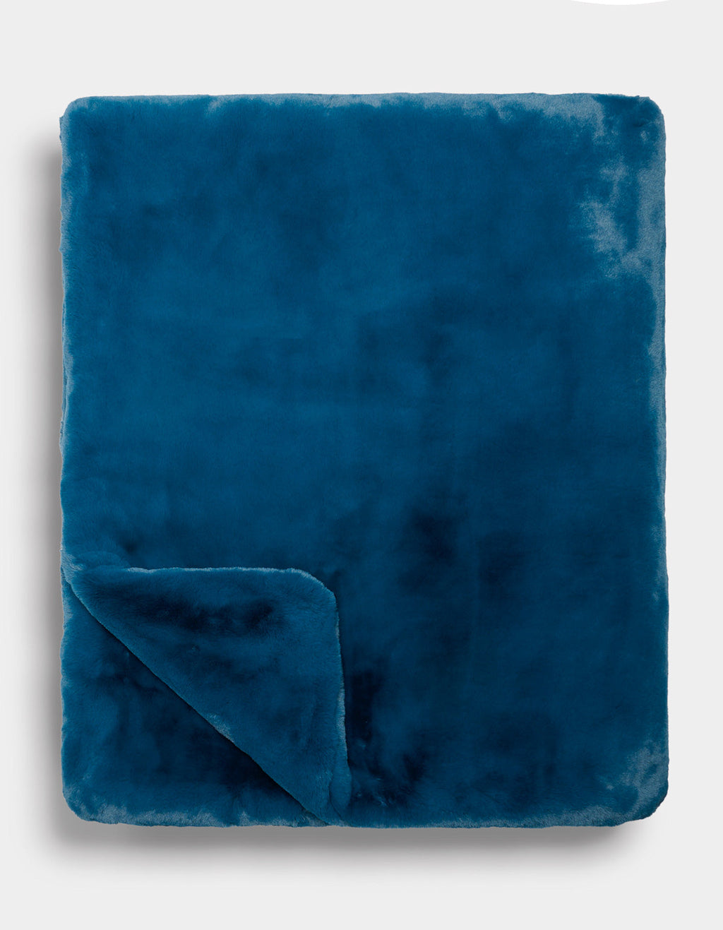A folded Superplush Cuddle Blanket by Cozy Earth in teal blue, with one corner turned up to reveal its luxuriously soft texture against a plain light background.|Color:Deep Water