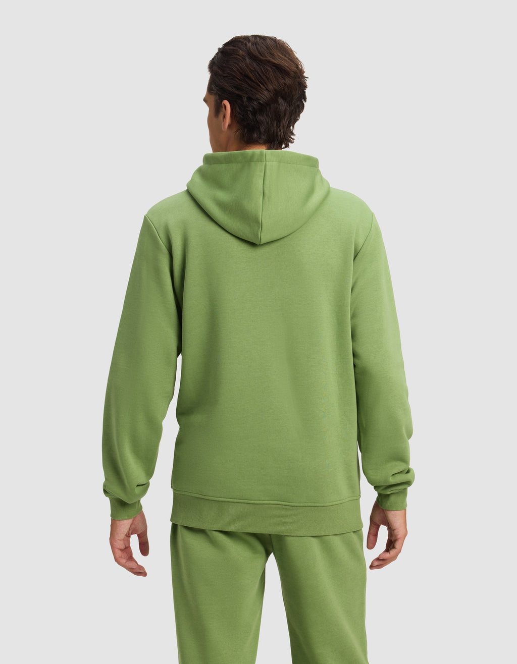 A man with short brown hair is seen from behind wearing the Cozy Earth Men's Cityscape Hoodie in light green, paired with matching sweatpants, standing against a plain light gray background.|Color:Clover