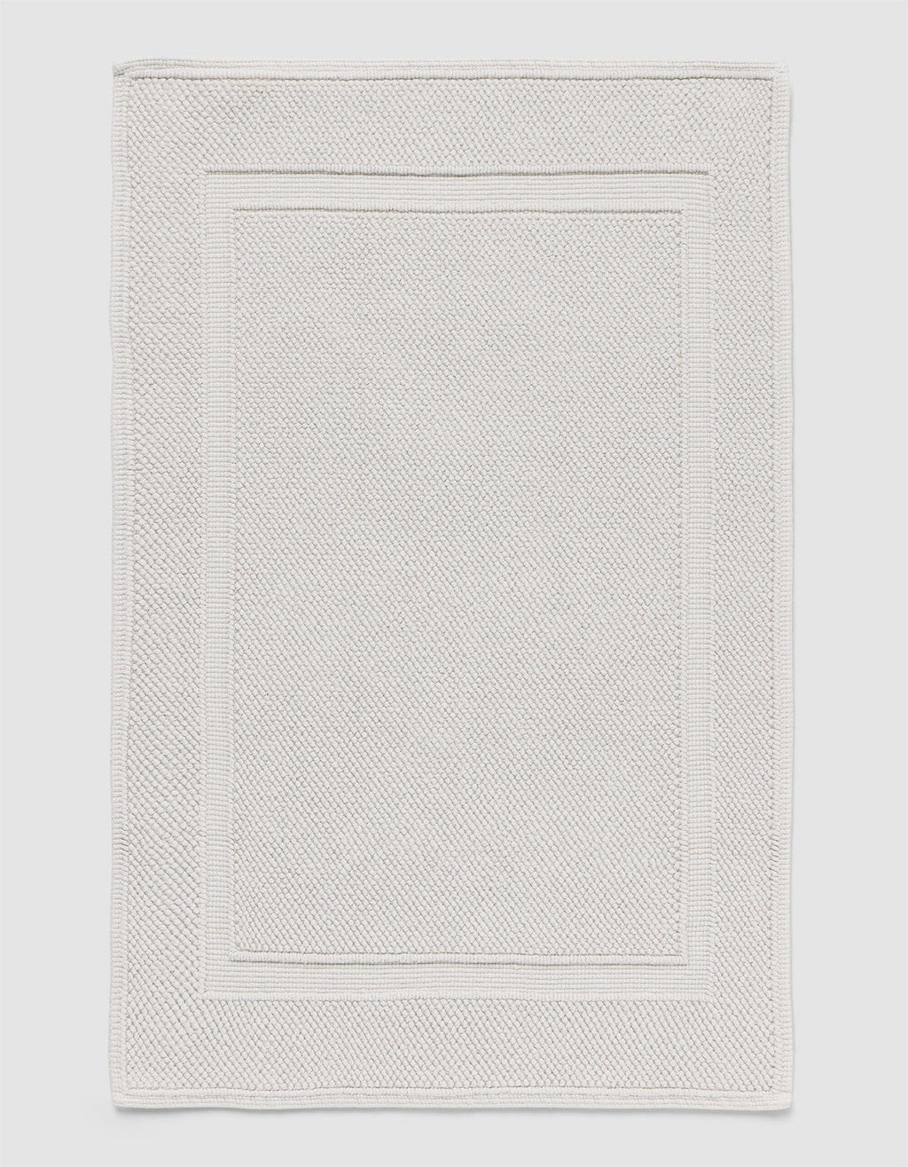 The Cozy Earth Classic Bath Mat features a rectangular shape, light color, subtle textured pattern, and elegant double border design on the edges.|Color:Light Grey
