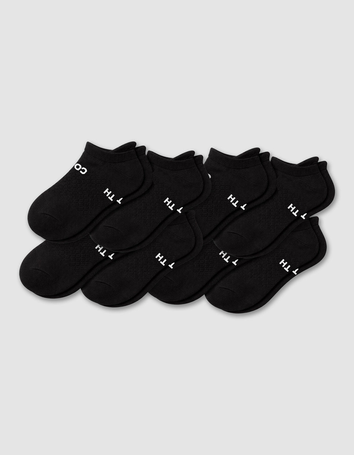 Eight pairs of Cozy Earth Men's Essential ankle socks in black are arranged in two rows on a plain light gray background, with some showing white text near the cuff.|Color:Black