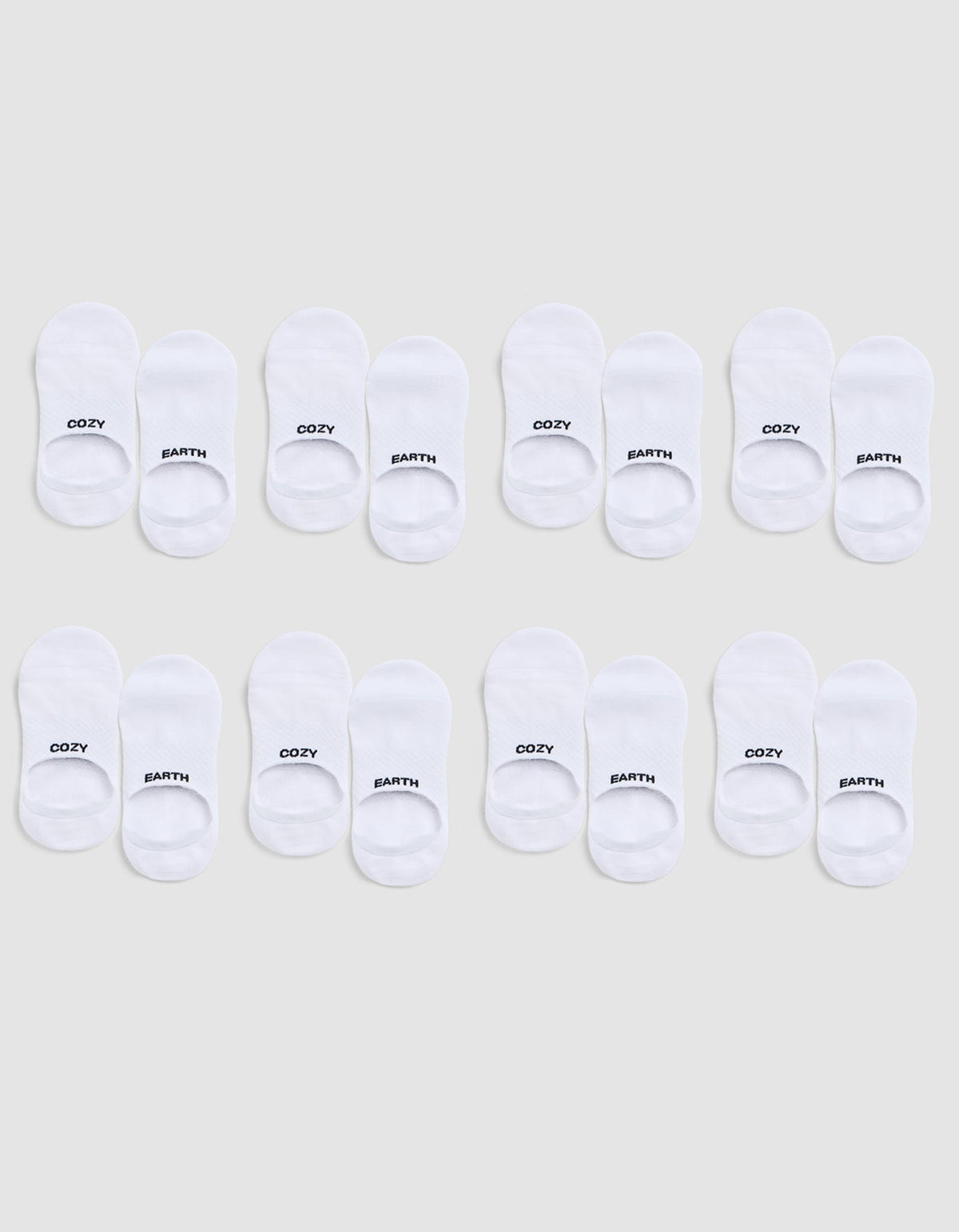 Eight pairs of white Essential No-Show Socks by Cozy Earth are arranged in three rows on a light gray background; each pair is labeled “COZY” on one sock and “EARTH” on the other. |Color:White