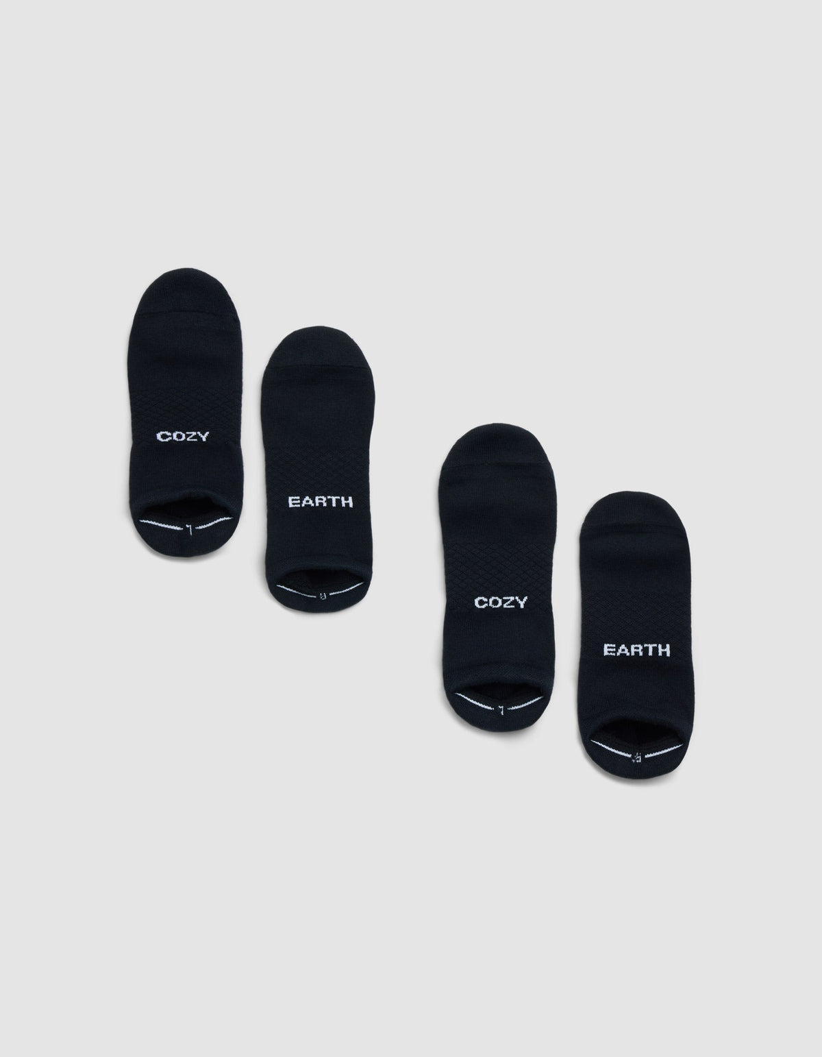 Two pairs of Cozy Earth Essential Ankle Socks in black are shown on a light gray background; each pair features "COZY" and "EARTH" in white lettering, both with matching style. |Color:Black