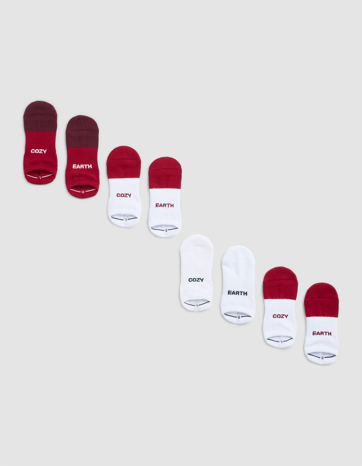 Eight pairs of Cozy Earth Essential Ankle Sock 4-Packs in red and white, arranged diagonally on a light grey background. Some socks feature "COZY" or "EARTH" labels.|Color:Crimson