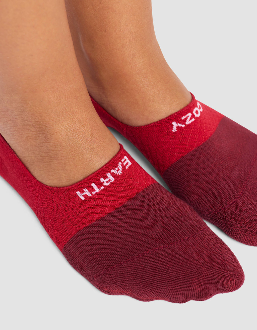 A close-up shows feet in Cozy Earth Women's Essential No-Show Socks, red with "EMPATHY" in white near the top edge, against a light gray background.|Color:Crimson