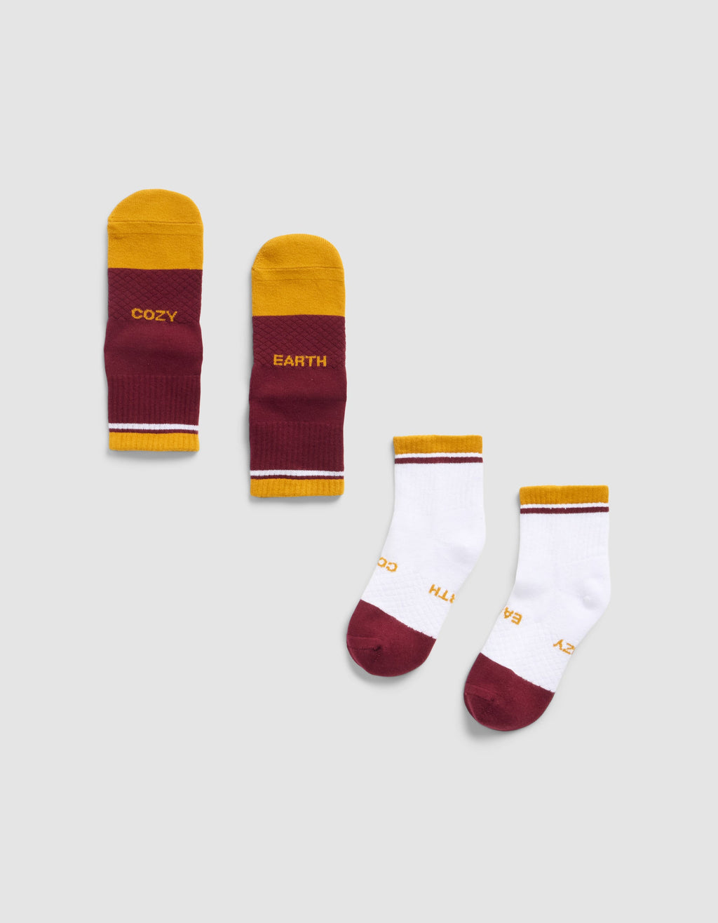 Two pairs of Cozy Earth Essential Quarter Socks: one maroon/yellow pair with "COZY" and "EARTH" on the soles, and one mostly white pair with maroon toes and yellow heels, both featuring the same branding.|Color:Burgundy