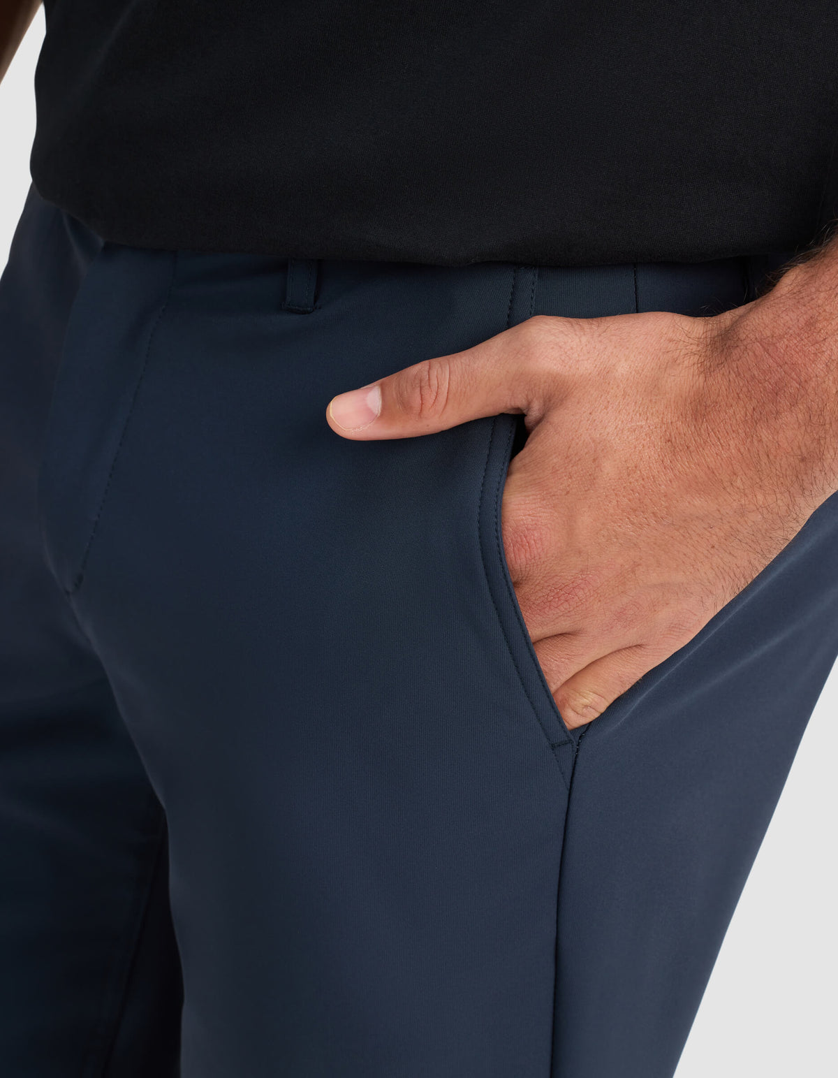 A close-up of a person wearing Cozy Earth Men's Everywhere Short in dark blue and a black shirt, with their right hand placed inside the short’s pocket.|Color:Eclipse