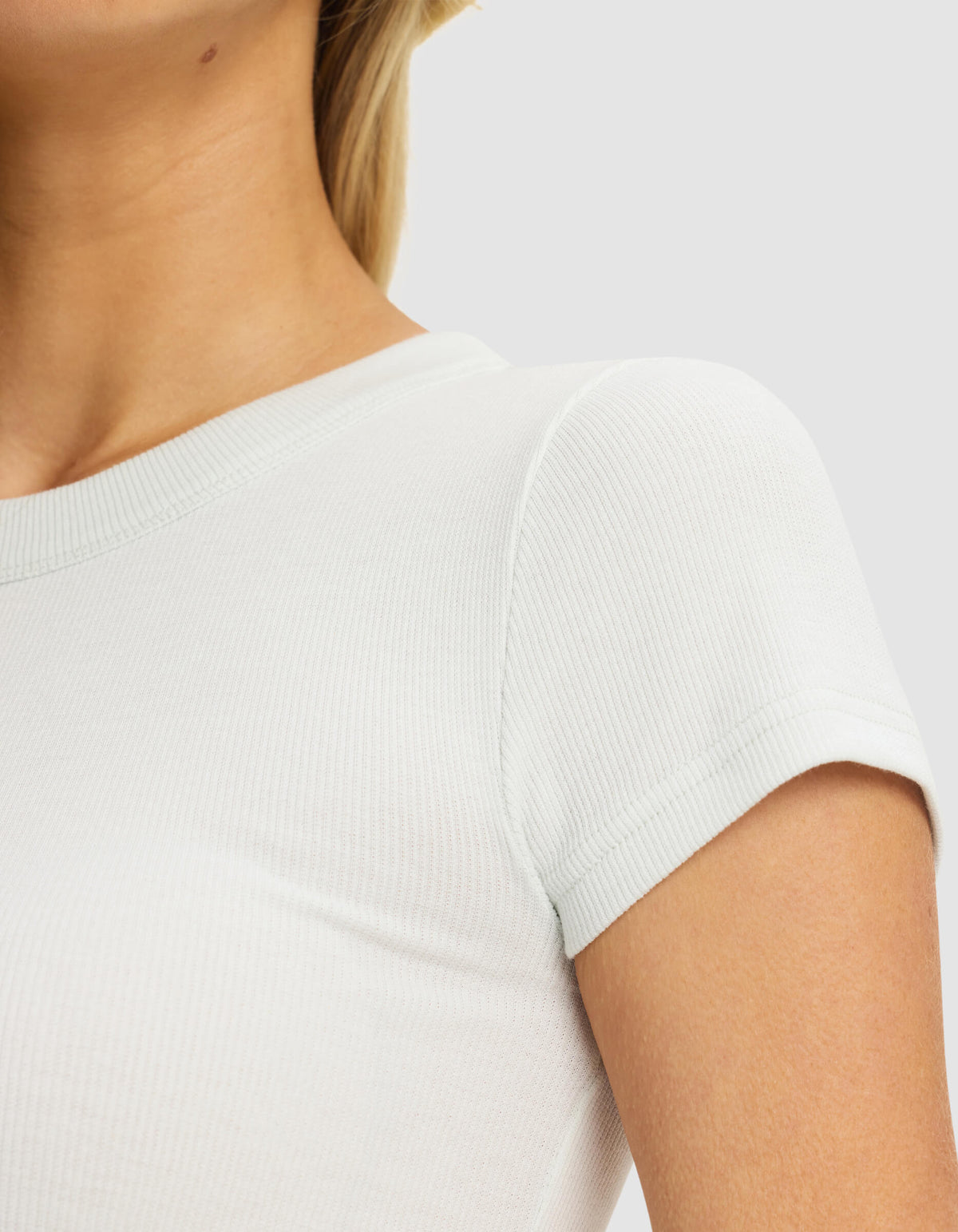 Close-up of a woman wearing the Cozy Earth Women's Fine Ribbed Tee in white, highlighting the ribbed texture, short sleeves, and upper torso against a plain light background.|Color:Vapor