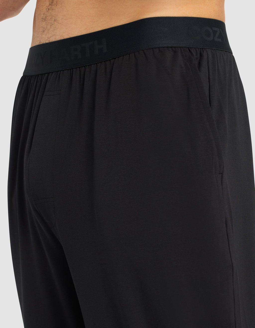 Close-up side view of a person wearing Cozy Earth Men's First Layer Pajama Pant, featuring an elastic waistband subtly printed with "COZY EARTH." The soft, smooth fabric enhances comfort.|Color:Jet Black